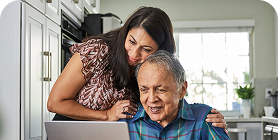 Man and woman looking down at a laptop in the kitchen